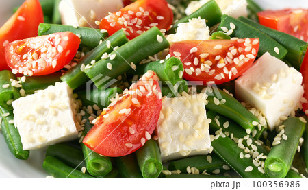 green bean salad with tomatoes, feta and sesame seeds close up. green bean salad with tomatoes, feta and sesame seeds close up. 100356986