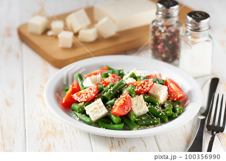 Fresh vegetarian vegetable salad with with tomatoes, feta and sesame seeds on a white wooden table, healthy food. Fresh vegetarian vegetable salad with with tomatoes, feta and sesame seeds on a white wooden table, healthy food. 100356990