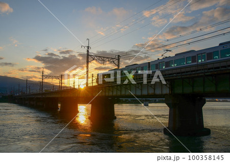 川にかかる鉄橋を渡る電車と朝日の輝き 川にかかる鉄橋を渡る電車と朝日の輝き 100358145