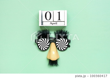 funny face - fake eyeglasses, nose and mustache, calendar date 01 April on green background Happy fools day concept 1st April party Holiday greetind card. 100360417