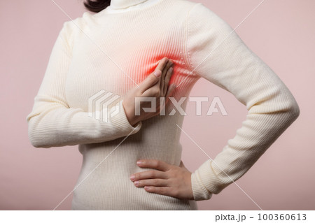 Woman hands checking lumps on her breast for signs of breast cancer on pink background. Healthcare concept. 100360613