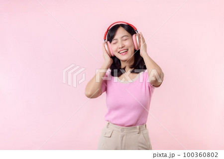 Smile pretty model person listen music song and enjoy dance with wireless headphone online audio radio sound. Positive fun exited joyful youth female woman sing on pink isolated background studio 100360802
