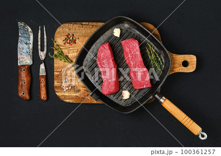 Overhead view of raw boneless beef loin steak on cast iron skillet Overhead view of raw boneless beef loin steak on cast iron skillet 100361257