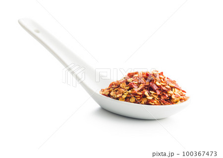 Dry chili pepper flakes in ceramic spoon. Crushed red peppers isolated on white background. Dry chili pepper flakes in ceramic spoon. Crushed red peppers isolated on white background. 100367473