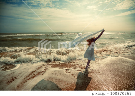 The young happy woman in a white dress with pareo on the beach on a summer sunny day The young happy woman in a white dress with pareo on the beach on a summer sunny day 100370265