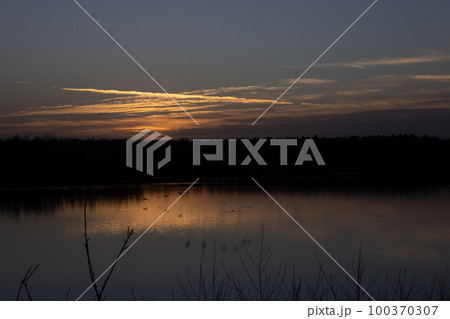 Dramatic sunset over a forest lake Dramatic sunset over a forest lake 100370307