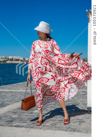 woman in a hat and dress enjoys the blue sea and summer. Welcome summer. 100370921
