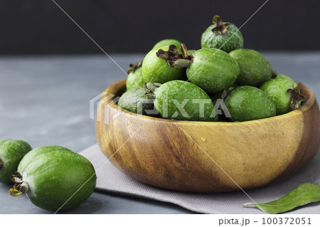 Green feijoa fruits in a wooden plate on a dark background. Tropical fruit feijoa. Set of ripe feijoa fruits. Copy space Green feijoa fruits in a wooden plate on a dark background. Tropical fruit feijoa. Set of ripe feijoa fruits. Copy space 100372051