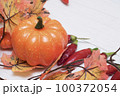 Pumpkin on a light background next to hot chili peppers and autumn maple leaves. 100372054