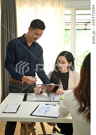 Asian male manager sharing ideas business strategy, discussing financial data with his colleagues at meeting 100372094