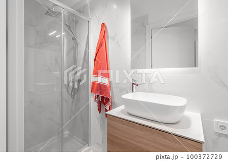 White compact bathroom with sink with mirror and glass-enclosed shower with a stylish renovation. Concept of a bathroom in a cozy apartment or country house. Copyspace White compact bathroom with sink with mirror and glass-enclosed shower with a stylish renovation. Concept of a bathroom in a cozy apartment or country house. Copyspace 100372729