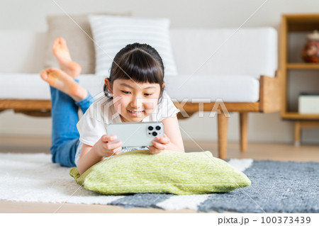 スマホで動画を見る小学生の女の子 スマホで動画を見る小学生の女の子 100373439