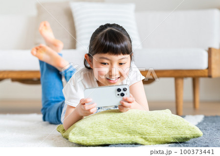 スマホで動画を見る小学生の女の子 スマホで動画を見る小学生の女の子 100373441
