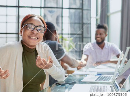 Beautiful young grinning professional Black woman in office 100373596