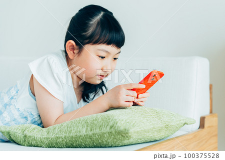 リビングでスマホを見る小学生の女の子 リビングでスマホを見る小学生の女の子 100375528