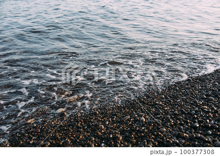 Seashore with pebbles and stones in the evening at sunset Seashore with pebbles and stones in the evening at sunset 100377308