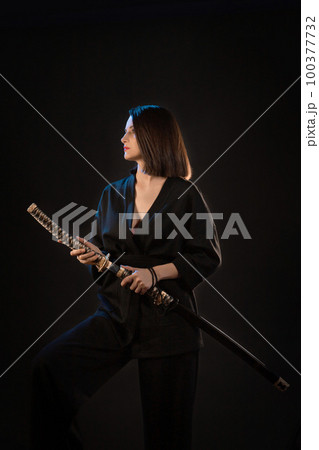 Young beautiful woman in black kimono with japanese sword on black background 100377732
