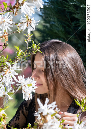 Brunette lady unites with nature breathing scent of flowers 100378507