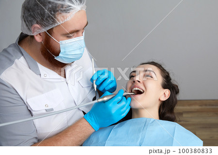 Dentist drilling tooth of female patient in dental chair Dentist drilling tooth of female patient in dental chair 100380833