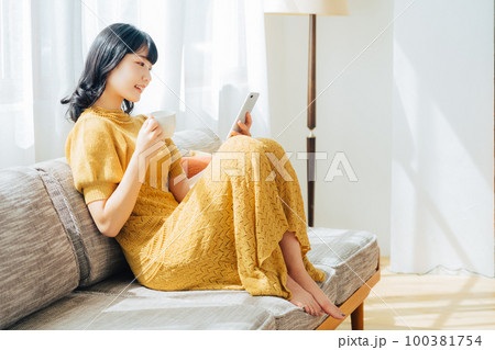 コーヒーを飲みながらスマホを見る女性 100381754