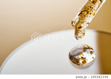 Pipette and gel cosmetic products with gold in a Petri dish on beige background Pipette and gel cosmetic products with gold in a Petri dish on beige background 100382346