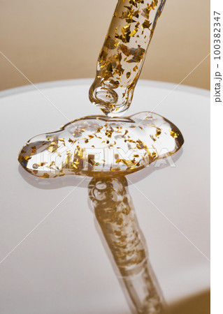 Pipette and gel cosmetic products with gold in a Petri dish on beige background Pipette and gel cosmetic products with gold in a Petri dish on beige background 100382347