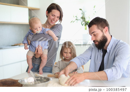 Young parents playing with children in the kitchen 100385497