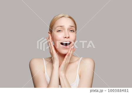 Happy surprised blonde woman isolated on grey background. Beauty, cosmetics, skincare, glamour 100388481