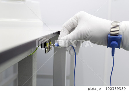 Bracelet on the hand of a man wearing ESD cloth and glove static resistance ESD bracelet or ground equipment, anti-static, used to safely ground is working. Semiconductor manufacturing. 100389389