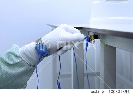 Bracelet on the hand of a man wearing ESD cloth and glove static resistance ESD bracelet or ground equipment, anti-static, used to safely ground is working. Semiconductor manufacturing. 100389391