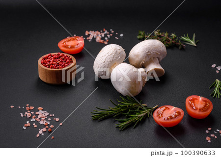 Fresh raw champignon mushrooms on a wooden cutting board with spices 100390633