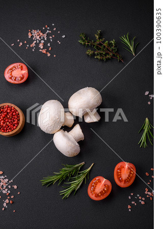 Fresh raw champignon mushrooms on a wooden cutting board with spices 100390635
