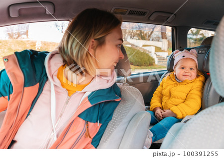 Car trip. Smiling mother looking back to her cute child is sitting at safe childrens backseat Car trip. Smiling mother looking back to her cute child is sitting at safe childrens backseat 100391255