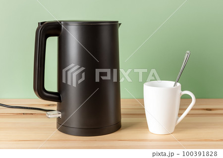 Matte black kettle and white mug on a wooden countertop. Matte black kettle and white mug on a wooden countertop. 100391828