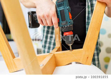 Assemble furniture. Man assembling chair. Furniture assembler with drill 100391855