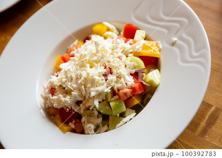 Dish of Balkan cuisine Shopska salad with cucumbers, tomatoes, bell peppers and brynza (salted sheep cheese) 100392783