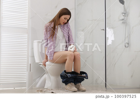 Woman with paper suffering from hemorrhoid on toilet bowl in rest room Woman with paper suffering from hemorrhoid on toilet bowl in rest room 100397525