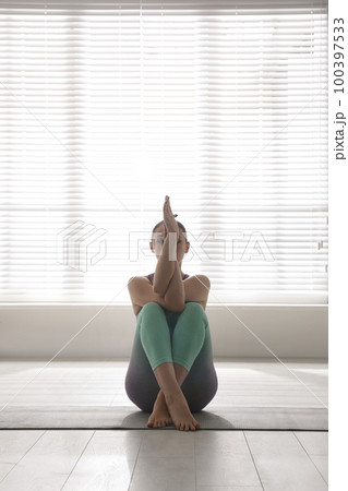 Woman practicing eagle asana in yoga studio. Garudasana pose 100397533