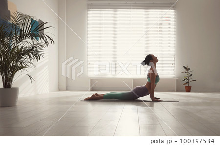 Woman practicing cobra asana in yoga studio. Bhujangasana pose 100397534