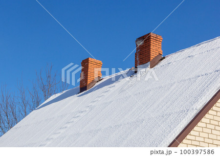 two red brick chimney on a white snowy roof two red brick chimney on a white snowy roof 100397586
