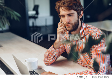 Young bearded man wearing casual shirt using his laptop computer Young bearded man wearing casual shirt using his laptop computer 100398309