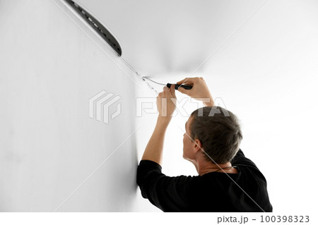 Repairman installing white stretch ceiling in room 100398323