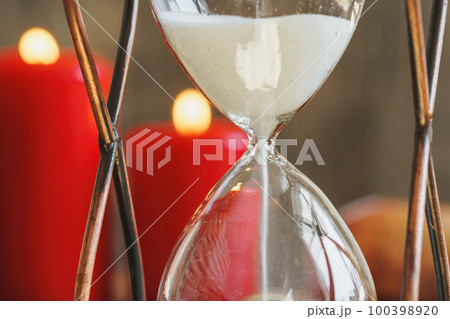Hourglass and red burning candles close up Hourglass and red burning candles close up 100398920