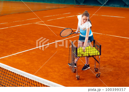 Young woman playing tennis at indoor tennis court 100399357