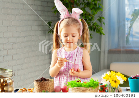 Little girl painting eggs for Easter at home 100400191
