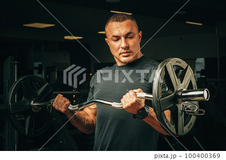Powerlifter with strong arms lifting barbell in a gym 100400369