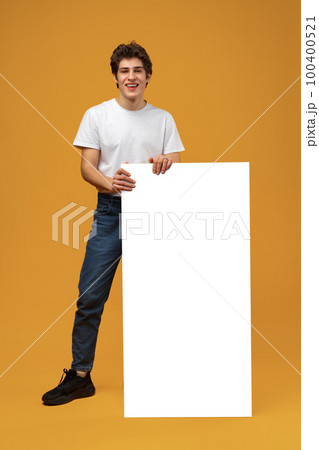 Cheerful guy demonstrate empty space blank offer on yellow background Cheerful guy demonstrate empty space blank offer on yellow background 100400521