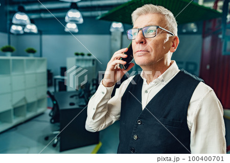Handsome mature businessman talking on mobile phone in the office 100400701