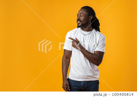 African man with beard pointing to copy space against yellow background African man with beard pointing to copy space against yellow background 100400814