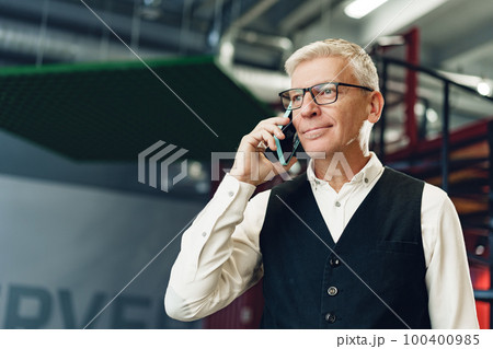 Handsome mature businessman talking on mobile phone in the office Handsome mature businessman talking on mobile phone in the office 100400985